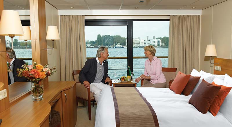 Two people sitting in a French Balcony stateroom on board a Viking river ship